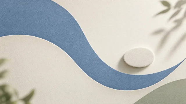 Flowing cream and blue paper curves beside a small raised ivory oval, with soft leaf shadows.