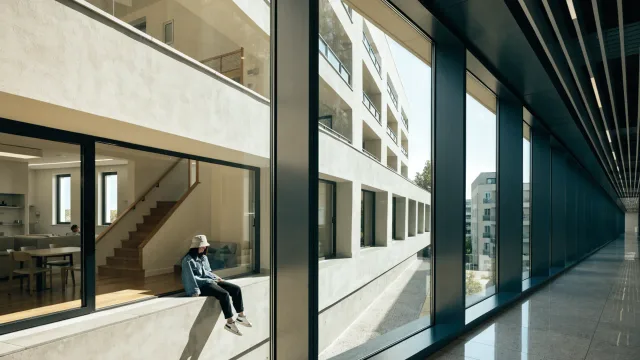 A bright accessible apartment reflected in the glass of a modern hospital corridor, with a hip model on the window ledge and no people